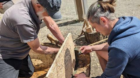 A volunteer and James Dilley putting the end board into a replica log boat, Stanwick Lake