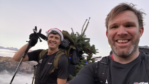 Ed Jackson and Ross Stirling on part of their climb. They are both smiling. Ed is wearing a Santa hat.
