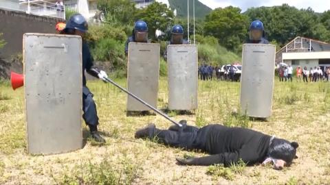 A man dressed in a bear costume is lying down after being subdued by police in an animal attack drill.