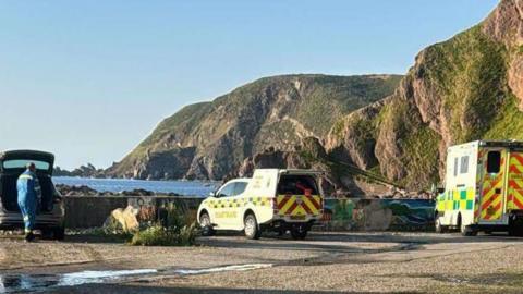 An ambulance and a coastguard rescue vehicle parked close to the rocky shore at Gardenstown in Aberdeenshire