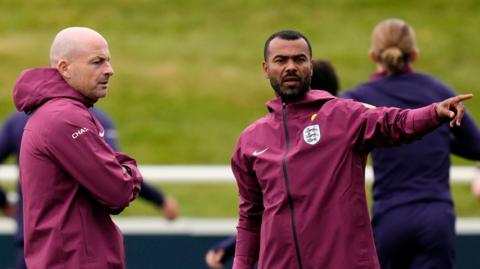 Lee Carsley speaks to Ashley Cole at an England training session