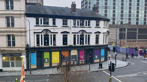 The Crown Pub in Birmingham. Dozens of windows and colourful boards can be seen at the front.
