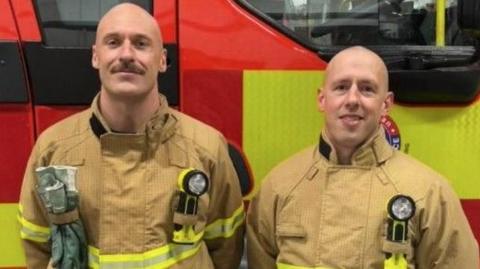 Kieran and Andy stand for a photo in front of a red fire truck