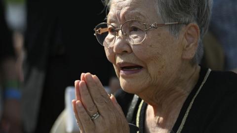 A local wearing a black shirt with glasses prays in front of the cenotaph for the victims of the world's first atomic bombing at the Peace Memorial Park