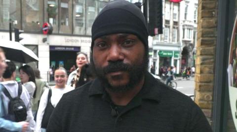 Shaun Thompson stands across the road from an entrance to London Bridge tube station