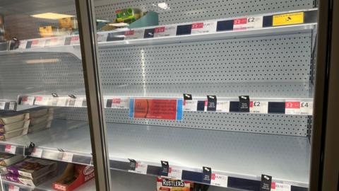 A chiller cabinet at the Co-Op in Loose Road, Maidstone, is left half empty with signs apologising for items not being in stock