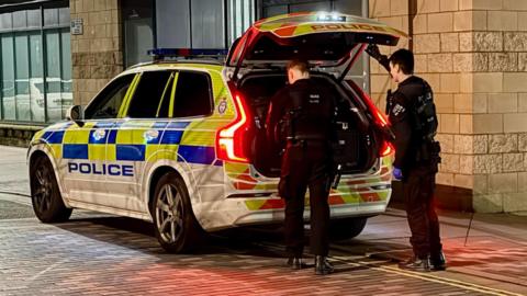 Police officers and a squad car at night