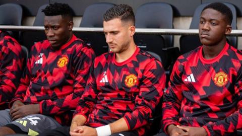 Manchester United midfielder Kobbie Mainoo and goalkeeper Andre Onana sitting on the bench at Fulham