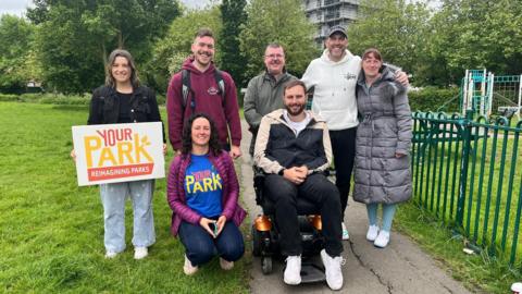 Campaigners from Your Park carrying placards and posing on a park pathway for a photo