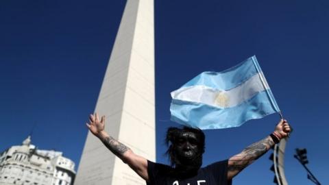 A demonstrator wearing a gorilla face mask waves an Argentine flag as he takes part in a protest against Argentina"s national government amid the coronavirus disease (COVID-19) outbreak, at the obelisk in Buenos Aires, Argentina, October 12, 2020