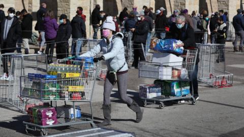 Customers leave with supplies as others wait at the Costco Wholesale store in Austin, Texas, on 20 February 2021