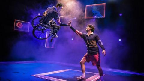 Ed Larkin suspended in the air in his wheelchair in West End show