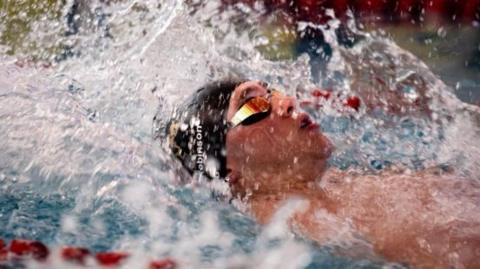 Harry Robinson swimming on his back in the pool.