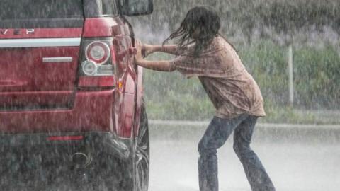 A girl gets into a car during driving rain