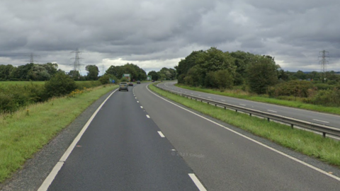 A dual carriageway, the A64, with some cars travelling on it.