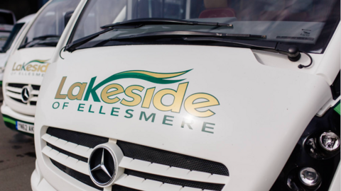 A zoomed in photo of a white mini bus with Lakeside of Ellesmere printed on the front and a Mercedes badge.