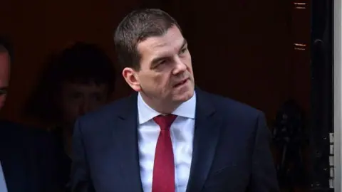 Starmer and Mandelson stood next to each other in suits, smiling.