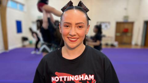 Georgie Leckey, looking at the camera, dressed in loose t-shirt with her Cheerleading group logo on it