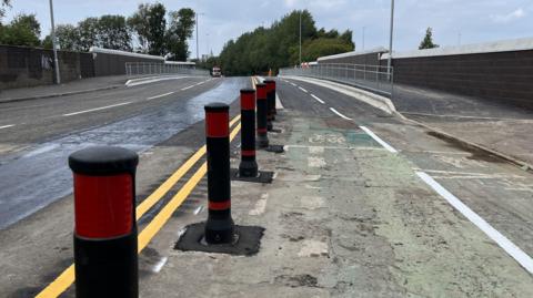 A new bridge with a two-way road and a cycle lane is displayed with a construction lorry parked in the back