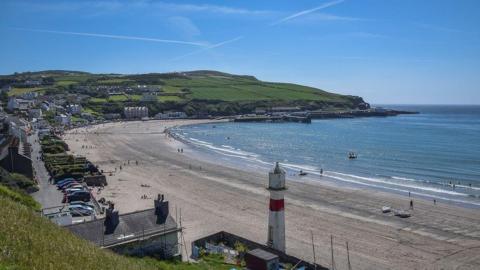 Port Erin bay with the lighthouse, headland and housing on a sunny day.