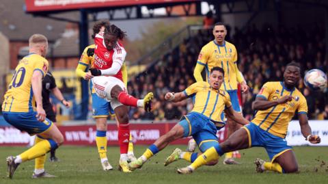 Arsenal's Eberechi Eze shooting a football against Mansfield Town defenders