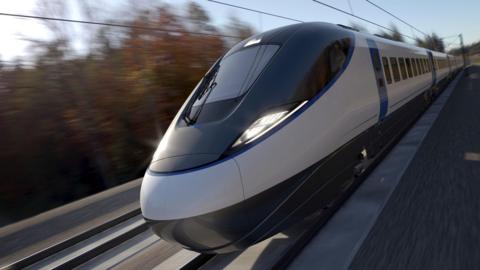 An artists' impression of an HS2 train. The train has a bullet shaped front with large glass windows and is running on rail lines through a background of trees which are blurred to imply the speed of the train.