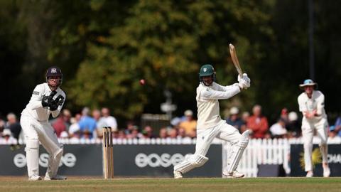Rehaan Edavalath plays an attacking shot on the off side at Cheltenham College, watched by Gloucestershire wicketkeeper James Bracey.