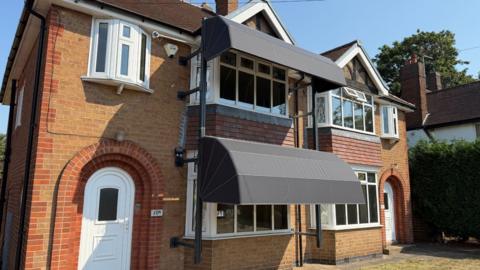 The semi-detached houses pictured on Ashby Road in Loughborough. The one on the left has dutch canopies attached to it, whilst the house on the right is unadapted. 