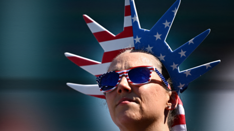 A woman wears a US flag crown and sunglasses