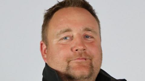 Jason Hutchings, Torbay councillor, in a black top with the collar up