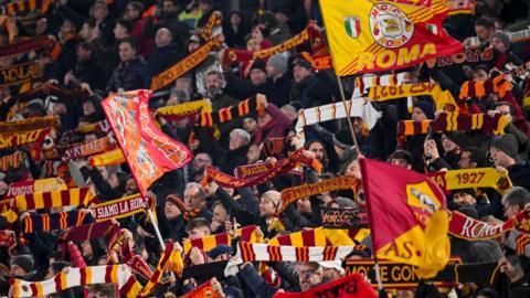 Roma fans hold flags and scarves