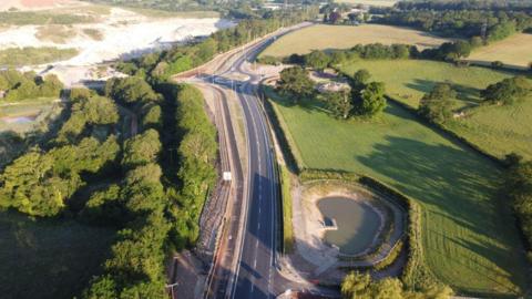 An aerial view of the A382, which is surrounded by trees and fields. No vehicles can be seen in this photo.