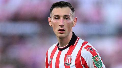 Robert Bozenik in action for Stoke City. He is wearing a home red and white striped shirt