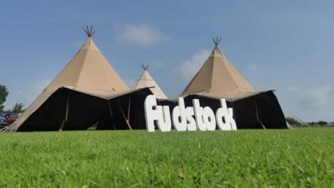 A fudstock sign and tents in a field