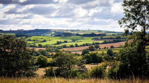 A scenic view of the Yorkshire Wolds. The sky is overcast with white clouds.