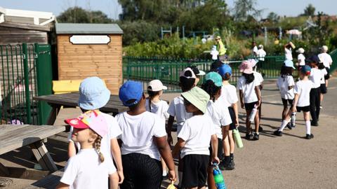 Schoolchildren lined up outside in the sunshine