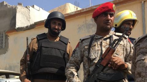 Saudi military and Civil Defence workers inspecting a building hit by a rocket from Yemen