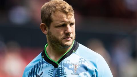 Joe Launchbury looks to his left during a match for Harlequins. He is wearing a sky blue coloured shirt.