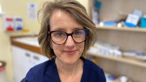 Rachel Harmer smiling to camera in her surgery room