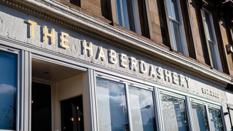 The entrance to the Haberdashery restaurant and events venue in Glasgow. The sun is shining on the building and the venue name is in large letters above the door