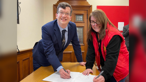 Eastbourne Borough Council leader Stephen Holt signing the contract next to Defiant Sports' managing director Loretta Lock
