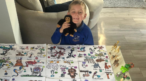 A little boy with 99 animals drawn in front of him for David Attenborough