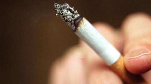A close up of a hand holding a cigarette