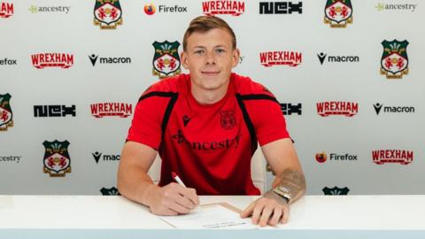 Wrexham's new goalkeeper Anthony Patterson signing papers at a desk