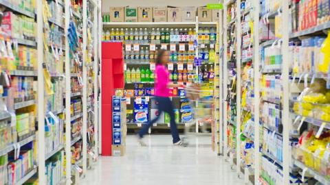 woman pushing a trolley in a supermarket isle 