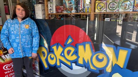 Isaac standing next to a Pokémon sign.