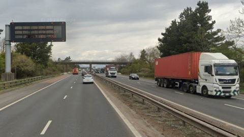A motorway in both directions with cars and a red lorry