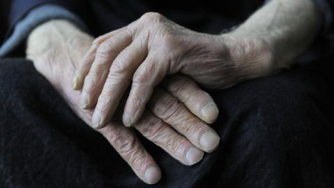 A close up of an elderly man's hands resting in one another. 