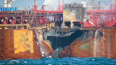 A picture shows a large hold in the side of a fire damaged oil tanker in the North Sea.