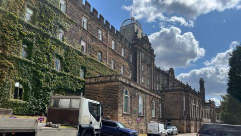 Listed Victorian stone county hall building covered in moss on left side 